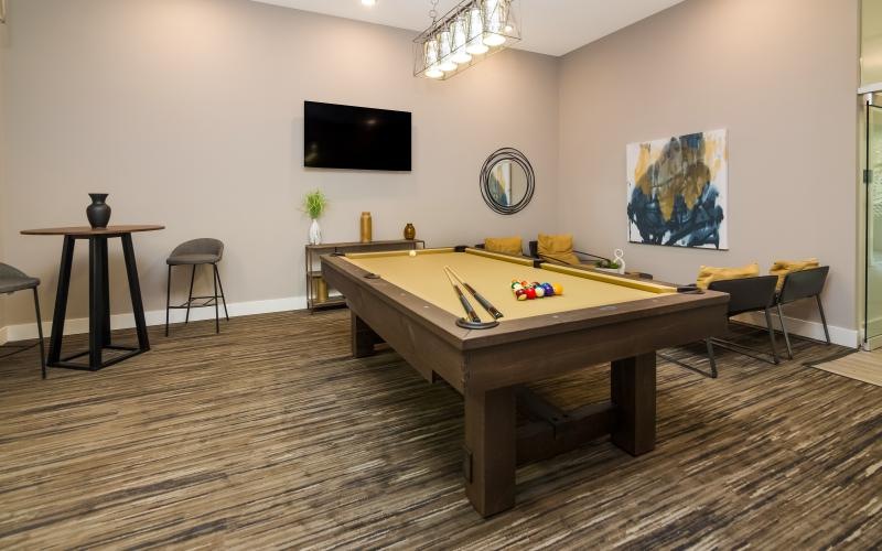 a room with a pool table and chairs